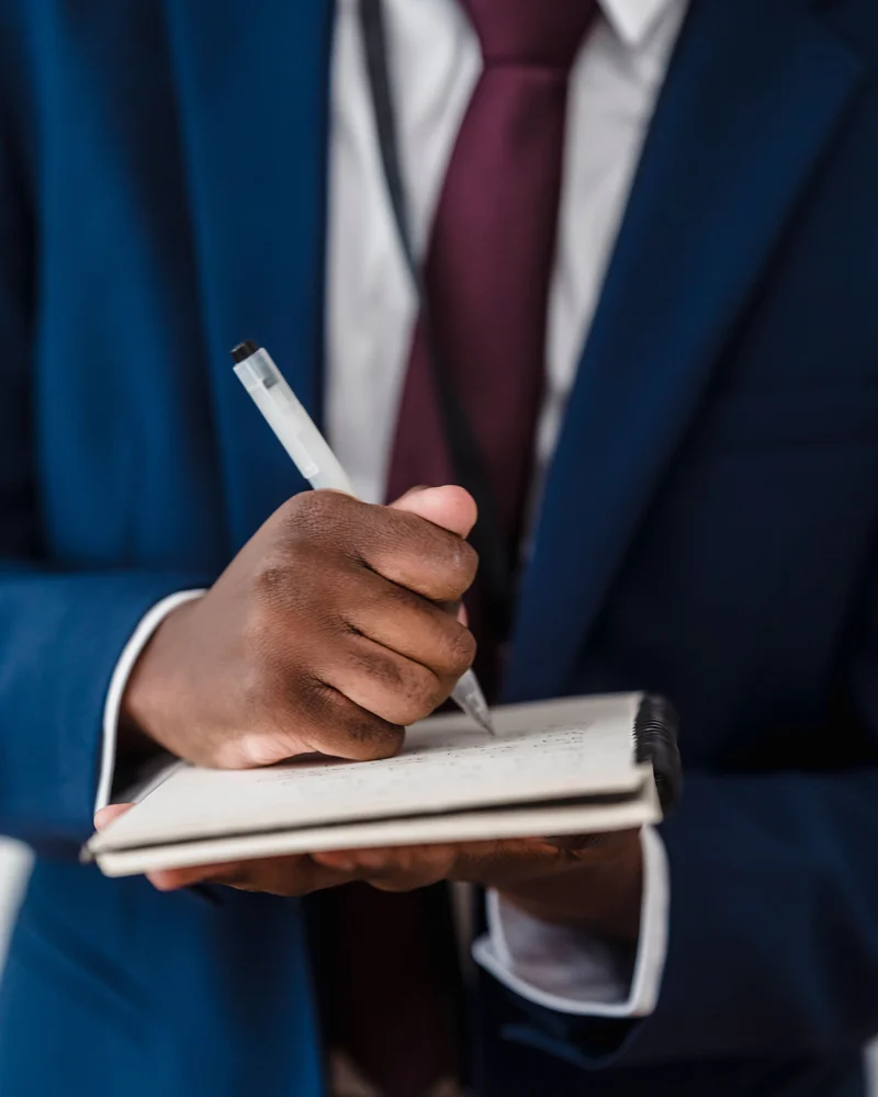 A man in a suit notes open items in his notebook.