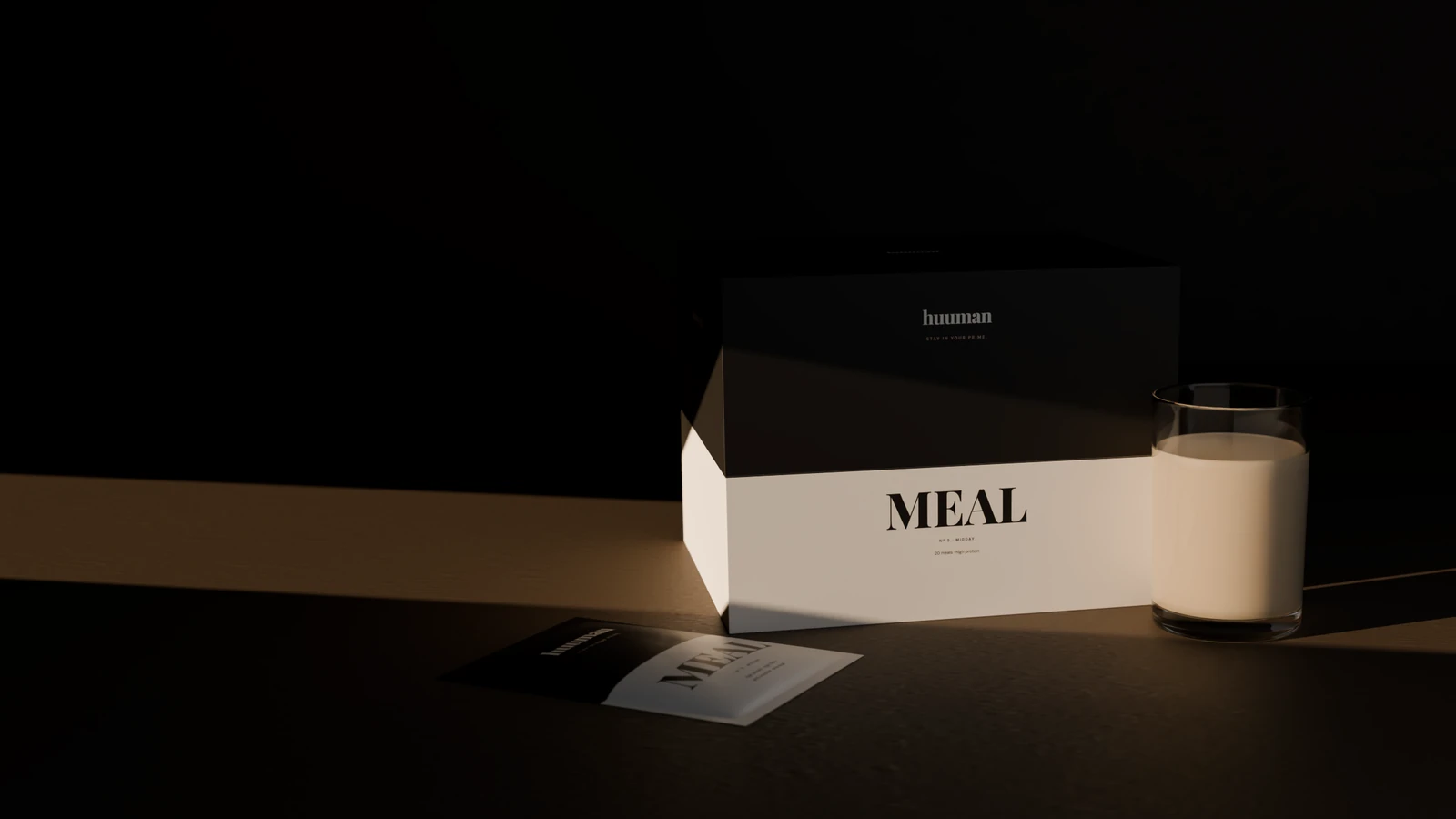 The MEAL box and a glass of MEAL on dark stone in a blade of low light, a sachet lying in front.