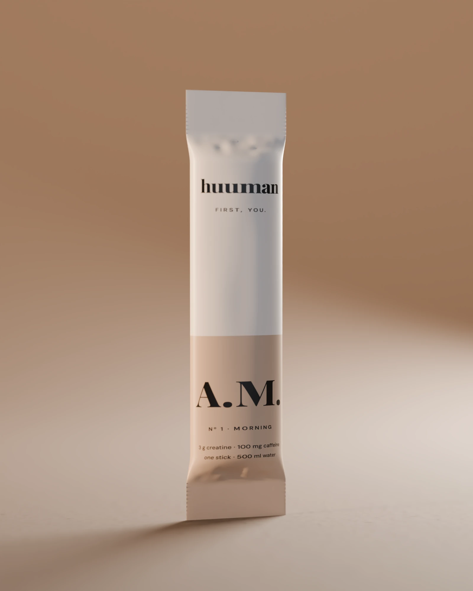 One A.M. stick standing in low morning sun: cream above, a sand-coloured band below, A.M. in black.